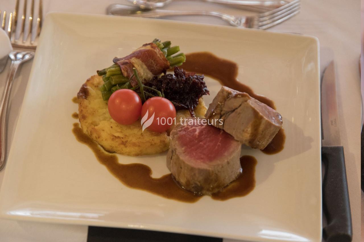 Assiette contenant un filet de viande, une galette de pommes de terre, des haricots verts enroulés de lard et des tomates…