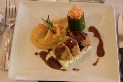Assiette contenant une mousse verte garnie de persil, accompagnée de tomates rôties et de points de sauce balsamique.
