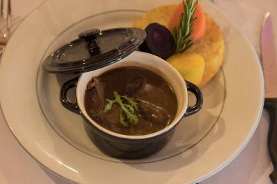 Assiette contenant une mousse verte garnie de persil, accompagnée de tomates rôties et de points de sauce balsamique.