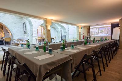 Salle de réunion avec tables disposées en U, chaises noires, bouteilles d'eau et écran de projection allumé.