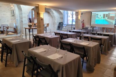 Salle de réunion avec tables disposées en U, chaises noires, bouteilles d'eau et écran de projection allumé.
