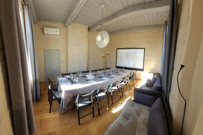 Salle de réunion avec tables disposées en U, chaises noires, bouteilles d'eau et écran de projection allumé.