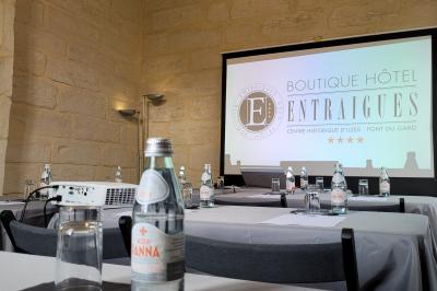 Salle de réunion avec tables disposées en U, chaises noires, bouteilles d'eau et écran de projection allumé.