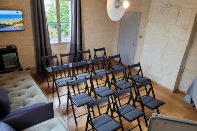 Salle de réunion avec tables disposées en U, chaises noires, bouteilles d'eau et écran de projection allumé.
