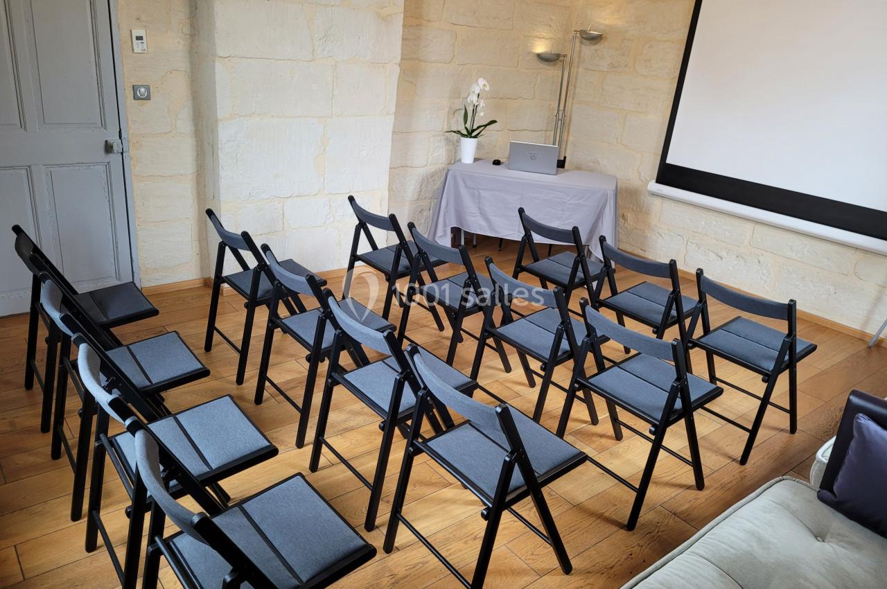 Salle de réunion équipée de chaises pliantes, d'un projecteur et d'une table avec un ordinateur portable.
