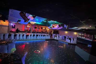 Salle de réception décorée avec des guirlandes et des lumières colorées, des invités assis et dansant.