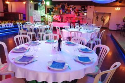 Salle de réception décorée avec des guirlandes et des lumières colorées, des invités assis et dansant.