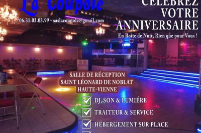 Salle de réception décorée avec des guirlandes et des lumières colorées, des invités assis et dansant.