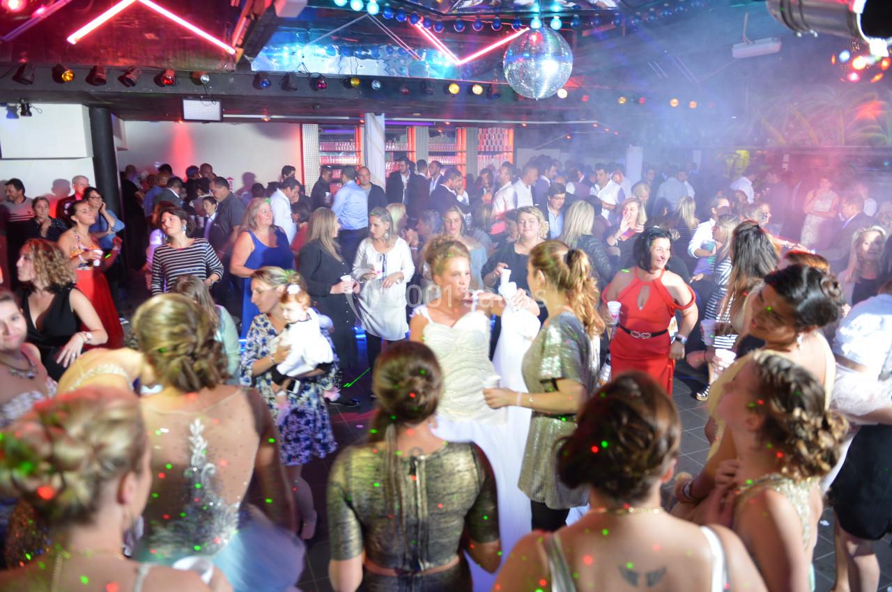 Groupe de personnes dans une salle de fête animée avec éclairages colorés et piste de danse.