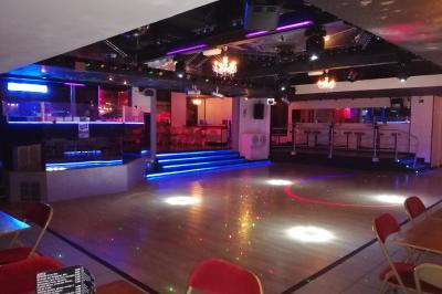 Salle de réception décorée avec des guirlandes et des lumières colorées, des invités assis et dansant.