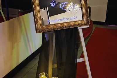 Salle de réception décorée avec des guirlandes et des lumières colorées, des invités assis et dansant.