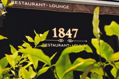 Façade d'un restaurant avec l'inscription ’1847 Restaurant-Lounge’, partiellement cachée par des feuilles vertes au premier…