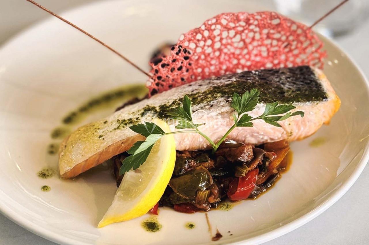 Filet de saumon grillé sur lit de légumes sautés, décoré de persil, citron et tuile rouge croustillante.