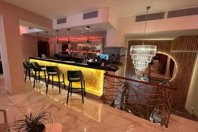 Salle de restaurant moderne avec tables dressées, chaises bleues, éclairage tamisé et bar illuminé en arrière-plan.