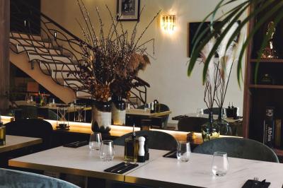 Salle de restaurant moderne avec tables dressées, chaises bleues, éclairage tamisé et bar illuminé en arrière-plan.