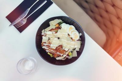Salle de restaurant moderne avec tables dressées, chaises bleues, éclairage tamisé et bar illuminé en arrière-plan.