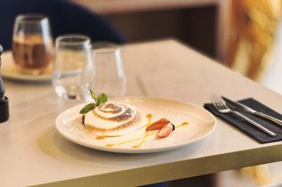 Salle de restaurant moderne avec tables dressées, chaises bleues, éclairage tamisé et bar illuminé en arrière-plan.