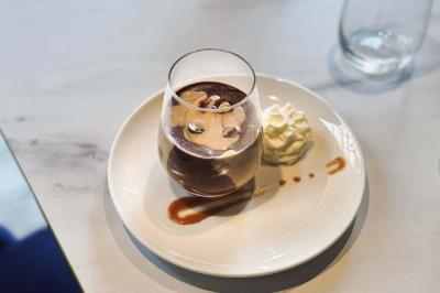 Salle de restaurant moderne avec tables dressées, chaises bleues, éclairage tamisé et bar illuminé en arrière-plan.