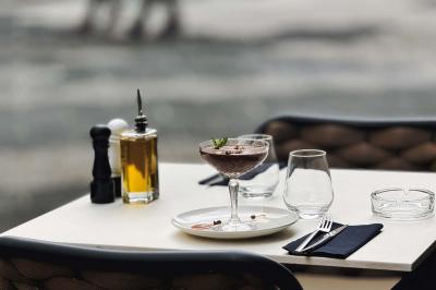 Salle de restaurant moderne avec tables dressées, chaises bleues, éclairage tamisé et bar illuminé en arrière-plan.