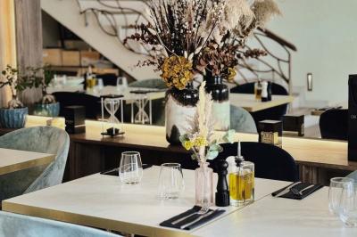 Salle de restaurant moderne avec tables dressées, chaises bleues, éclairage tamisé et bar illuminé en arrière-plan.