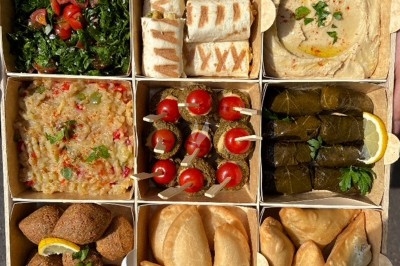 Assiette de wraps garnis autour d'un bol de sauce blanche, accompagnée de légumes marinés et de tranches de tomate.