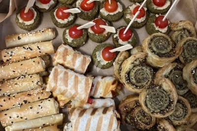 Assiette de wraps garnis autour d'un bol de sauce blanche, accompagnée de légumes marinés et de tranches de tomate.