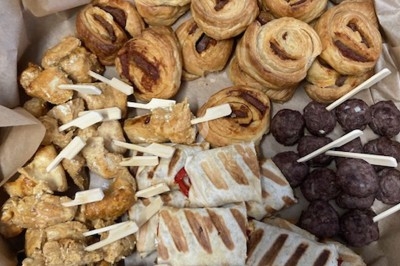 Assiette de wraps garnis autour d'un bol de sauce blanche, accompagnée de légumes marinés et de tranches de tomate.