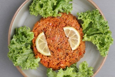 Assiette de wraps garnis autour d'un bol de sauce blanche, accompagnée de légumes marinés et de tranches de tomate.
