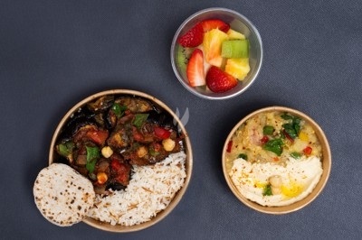 Assiette de wraps garnis autour d'un bol de sauce blanche, accompagnée de légumes marinés et de tranches de tomate.