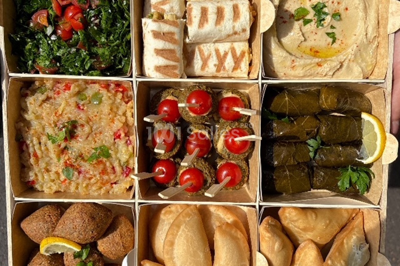 Plateau compartimenté contenant mezzés variés : taboulé, houmous, feuilles de vigne, brochettes, samboussek et falafels.