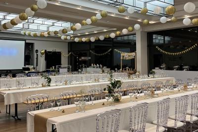 Entrée d'un bâtiment blanc entouré d'arbres, avec des portes vitrées illuminées par une lumière intérieure.