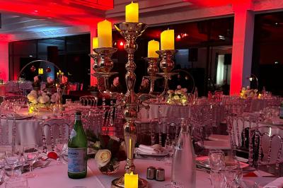 Entrée d'un bâtiment blanc entouré d'arbres, avec des portes vitrées illuminées par une lumière intérieure.