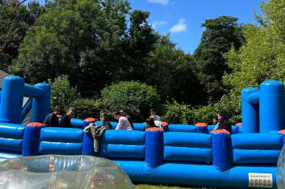 Entrée d'un bâtiment blanc entouré d'arbres, avec des portes vitrées illuminées par une lumière intérieure.