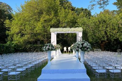 Table dressée avec des chaises transparentes, ornée de compositions florales tropicales colorées et de bougies.