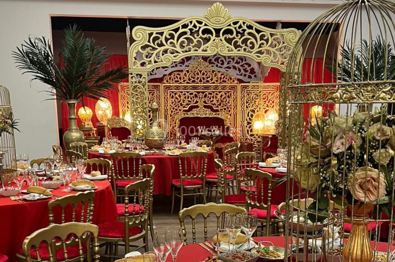 Salle décorée dans un style oriental avec des tables dressées, des chaises dorées, des cages dorées et des ornements…