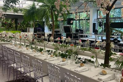 Table dressée avec des chaises transparentes, ornée de compositions florales tropicales colorées et de bougies.