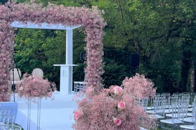 Table dressée avec des chaises transparentes, ornée de compositions florales tropicales colorées et de bougies.