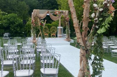 Table dressée avec des chaises transparentes, ornée de compositions florales tropicales colorées et de bougies.