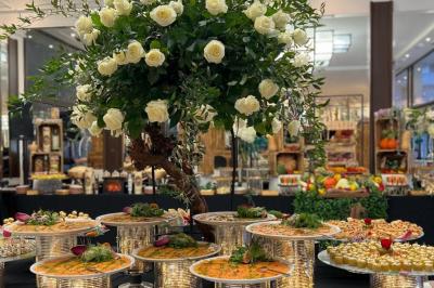 Table dressée avec des chaises transparentes, ornée de compositions florales tropicales colorées et de bougies.