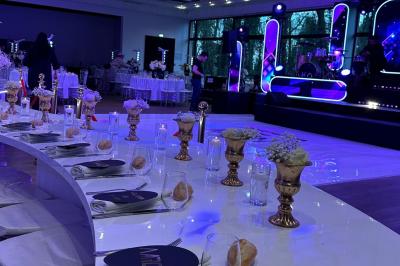 Table dressée avec des chaises transparentes, ornée de compositions florales tropicales colorées et de bougies.