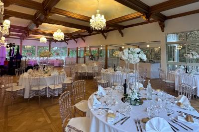 Table dressée avec des chaises transparentes, ornée de compositions florales tropicales colorées et de bougies.