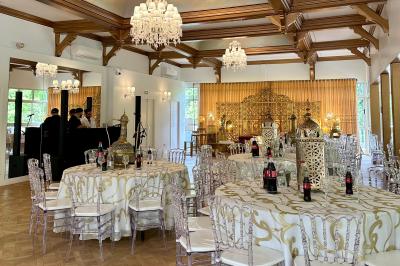 Table dressée avec des chaises transparentes, ornée de compositions florales tropicales colorées et de bougies.