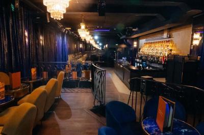 Un liquide enflammé est versé d'une petite carafe dans un verre rempli de glaçons sur une table.