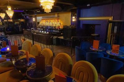 Un liquide enflammé est versé d'une petite carafe dans un verre rempli de glaçons sur une table.