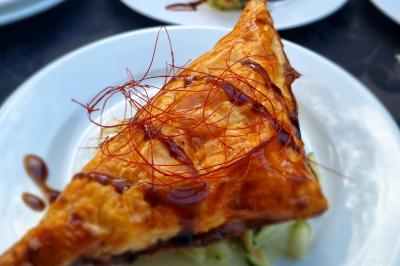 Huîtres gratinées garnies de fromage et épices, présentées sur un plateau en bois, avec légumes en arrière-plan.