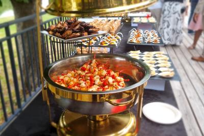 Huîtres gratinées garnies de fromage et épices, présentées sur un plateau en bois, avec légumes en arrière-plan.