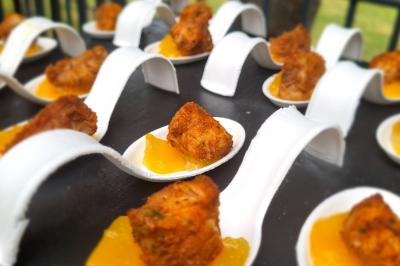 Huîtres gratinées garnies de fromage et épices, présentées sur un plateau en bois, avec légumes en arrière-plan.