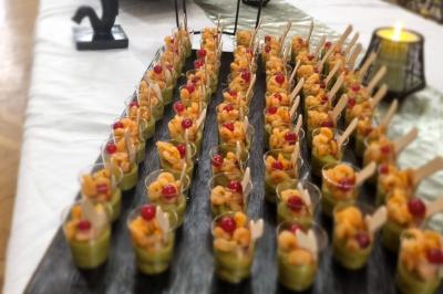 Huîtres gratinées garnies de fromage et épices, présentées sur un plateau en bois, avec légumes en arrière-plan.