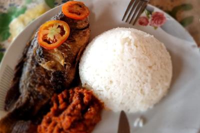 Huîtres gratinées garnies de fromage et épices, présentées sur un plateau en bois, avec légumes en arrière-plan.