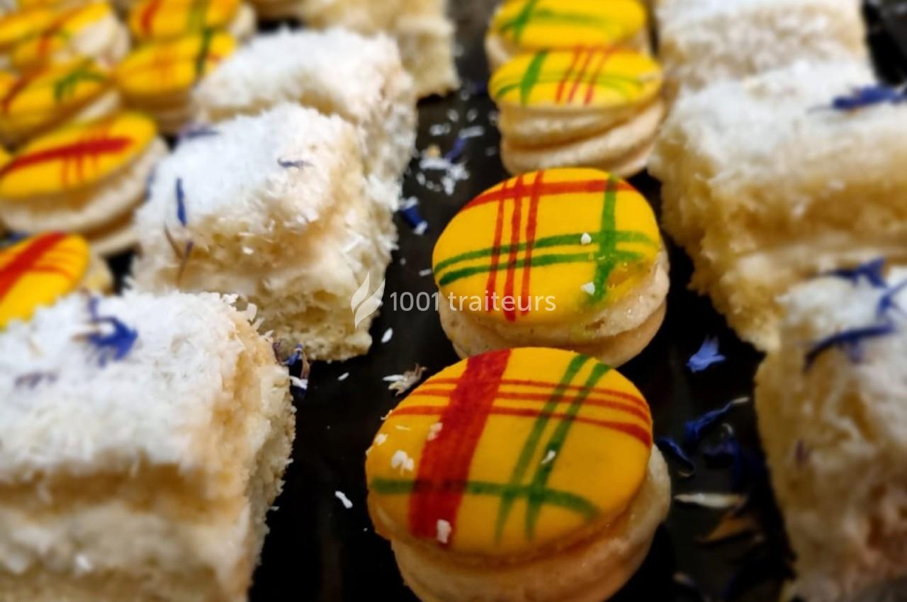 Pâtisseries colorées, dont des macarons jaunes décorés de lignes rouges et vertes, et des gâteaux saupoudrés de noix de coco.